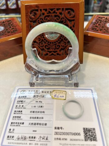 A white and green jade bracelet sitting on top of a table.