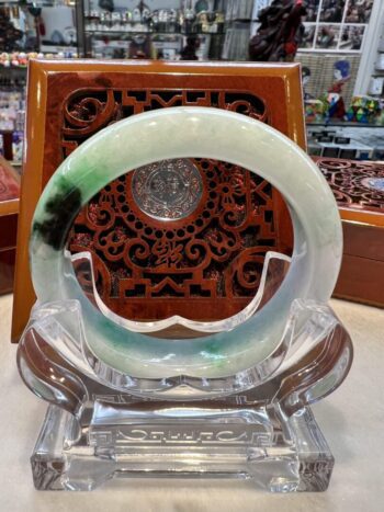 A green and white bracelet sitting on top of a glass display.