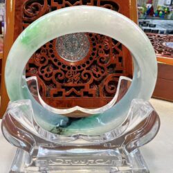 A clear glass sculpture with a green and blue ring.