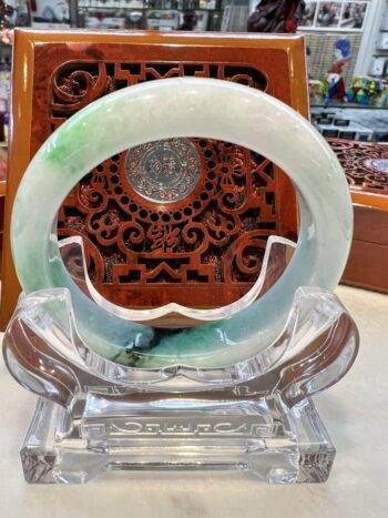 A clear glass sculpture with a green and blue ring.