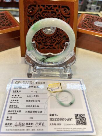 A green jade bracelet sitting on top of a table.