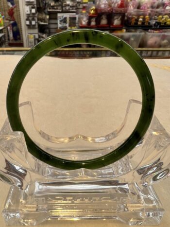 A green bracelet sitting on top of a glass table.