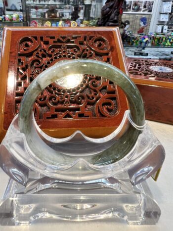 A glass sculpture of an open circle on top of a wooden stand.