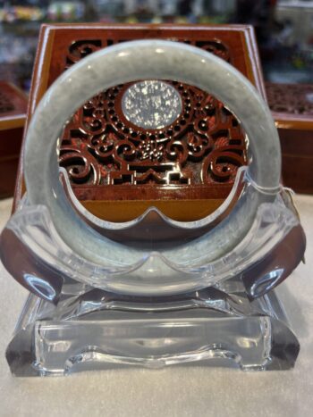 A glass clock with a round face and a wooden carved pattern.