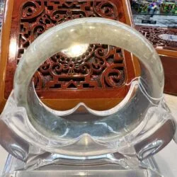 A clear glass bracelet sitting on top of a wooden table.