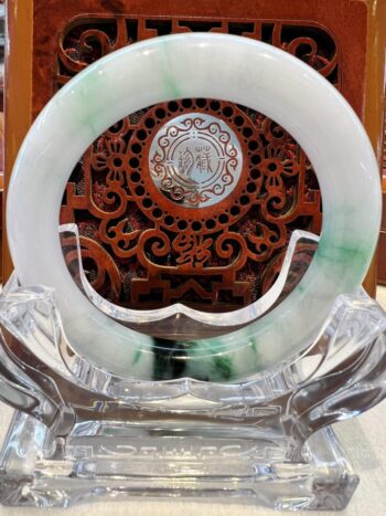 A green and white circular glass plate on top of a wooden stand.