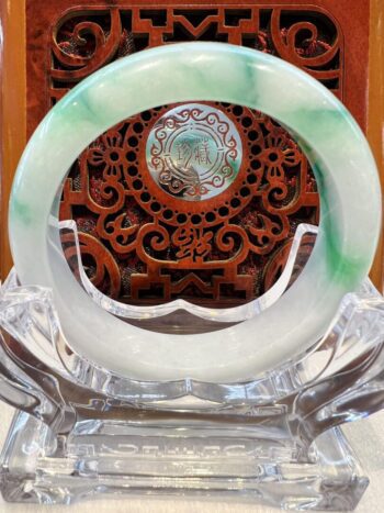 A green and white jade ring sitting on top of a table.