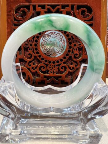 A green and white jade bangle sitting on top of a table.