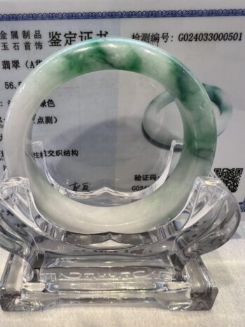 A green and white bracelet sitting on top of a glass display.