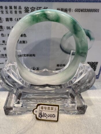 A green and white bracelet sitting on top of a glass display.