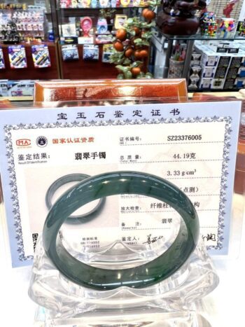 A green jade bangle is sitting on top of a certificate.