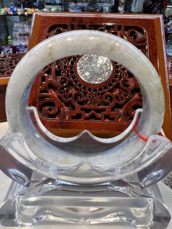 A white jade bracelet sitting on top of a clear glass bowl.