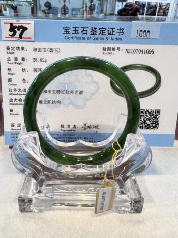 A green jade bangle is sitting on top of a certificate.