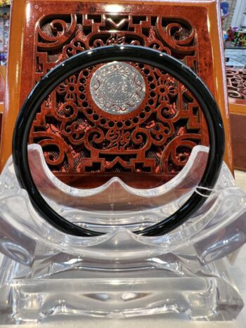 A black plastic headband sitting on top of a wooden stand.