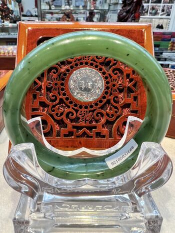 A green and brown clock on display in front of an ornate wooden wall.