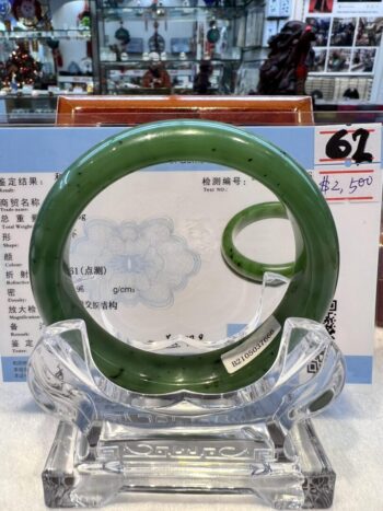 A green bangle sitting on top of a clear glass table.