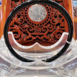 A black plastic bangle sitting on top of a wooden table.