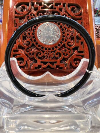 A black plastic bangle sitting on top of a wooden table.