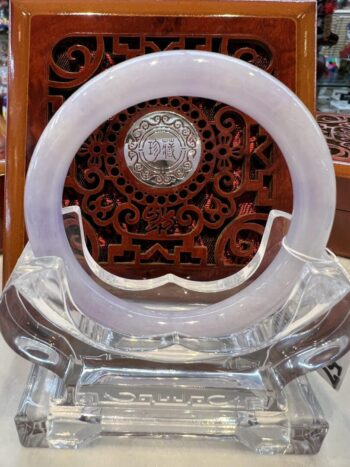 A white circular clock sitting on top of a clear glass stand.