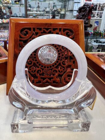 A glass sculpture of an open circle on top of a wooden stand.