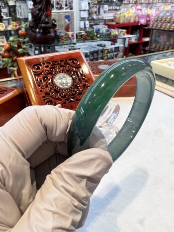 A person holding a glass plate in front of a wooden box.