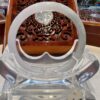 A clear plastic chair with a wooden carved table in the background.