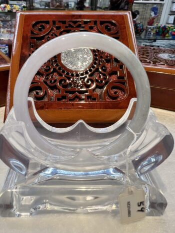 A clear plastic chair with a wooden carved table in the background.