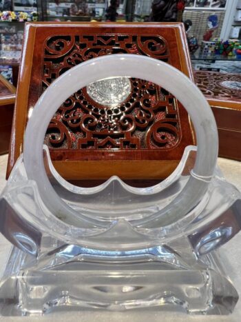 A clear plastic chair with a wooden carved table in the background.