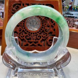 A green and white bangle sitting on top of a clear glass.