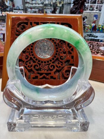 A green and white bangle sitting on top of a clear glass.