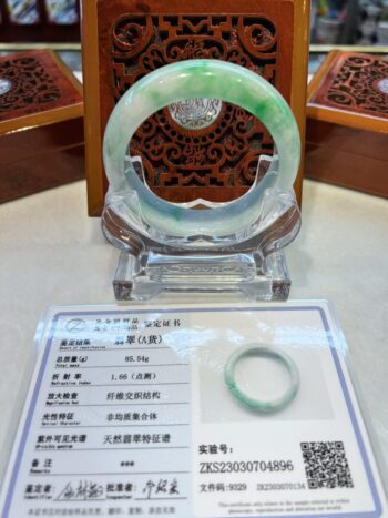 A green and white jade bangle sitting on top of a table.