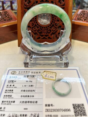 A green and white jade bangle sitting on top of a table.