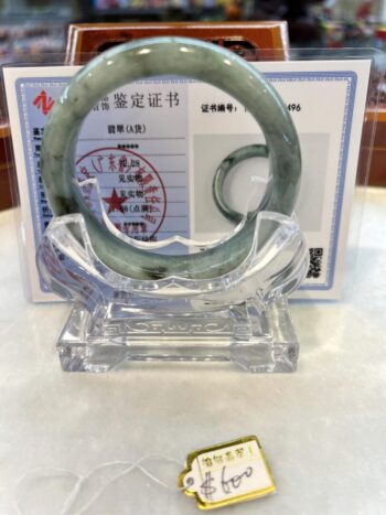 A green jade bangle sitting on top of a clear glass display.