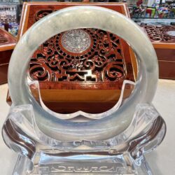 A large white jade bangle sitting on top of a glass table.