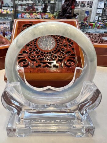 A large white jade bangle sitting on top of a glass table.