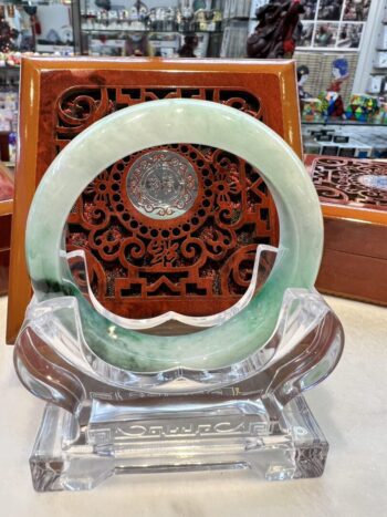 A green jade bracelet sitting on top of a glass display.