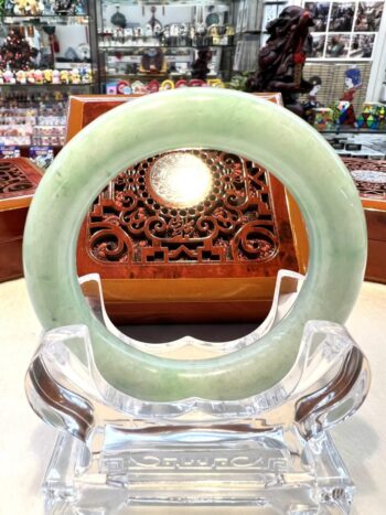 A green jade bangle sitting on top of a glass table.