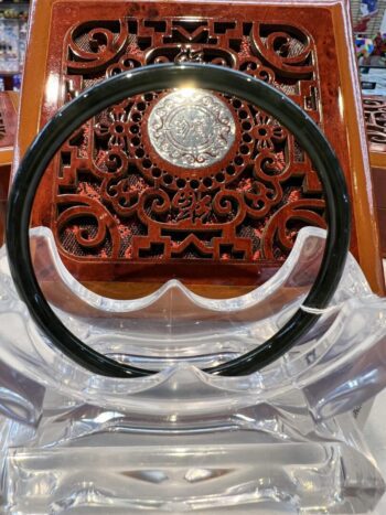 A black and clear plastic chair with a wooden carved wall behind it.