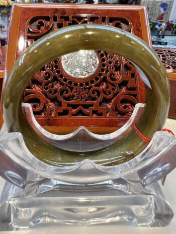 A large green bangle sitting on top of a clear plastic stand.