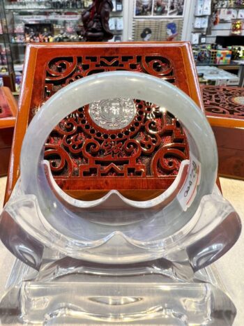 A clear plastic chair with an ornate wooden carving.