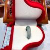 A red and white piano shaped box with a green instrument inside.