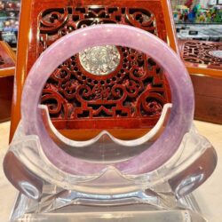 A pink bracelet sitting on top of a clear stand.