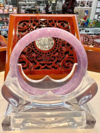 A pink bracelet sitting on top of a clear stand.