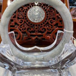 A large round glass clock with a carved wooden face.