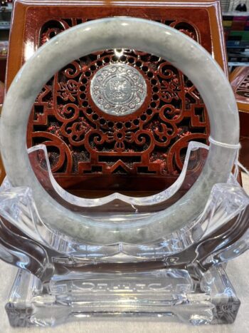 A large round glass clock with a carved wooden face.