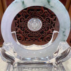 A round green and white marble plate on top of a clear glass stand.