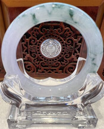 A round green and white marble plate on top of a clear glass stand.