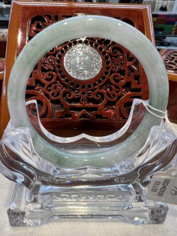 A round green jade ring sitting on top of a glass stand.