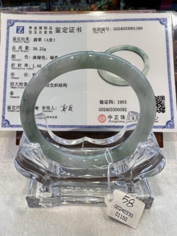 A green jade bangle is displayed on top of an official certificate.