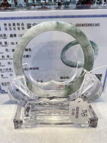 A green jade bangle is on display in a glass case.